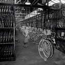 10414789
&copy; NMeM - Walter Nurnberg
Female worker with overhead loading belt before assembly, British Cycle Co. England, 1950s.
