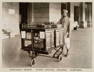 10446180
&copy; National Railway Museum
Vendor selling sweets and cakes at Poona Station, India, c 1930.